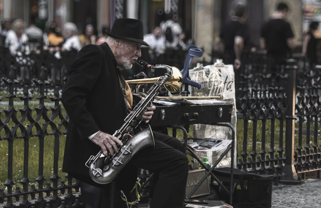 pexels photo 1384605 Elderly musician playing saxophone in Prague's lively streets, capturing the essence of street art.