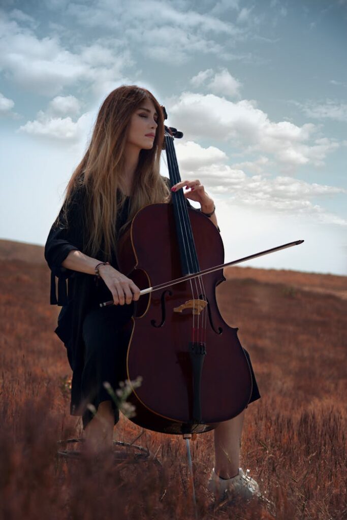 pexels photo 2960156 A young woman plays the cello in a serene outdoor setting under a bright sky.